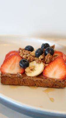 Our Protein Toast! A toast with your choice of almond or peanut butter, banana, strawberries, granola and topped with syrup.