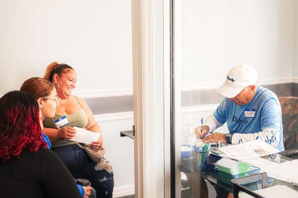 A mom and her two daughters gratefully look on as a IDignity team member works to get their identification documents.