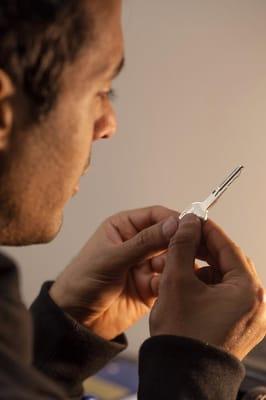 Here we have a locksmith focusing on a job. It looks like he is trying to determine if he has the right blank before cutting ...