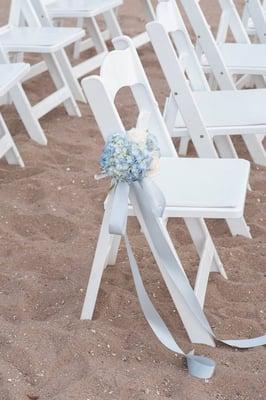 A single chair for the wedding ceremony decked in pew flowers.