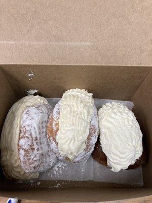 Two powered sugar cream donuts and a chocolate frosted cream filled donut.