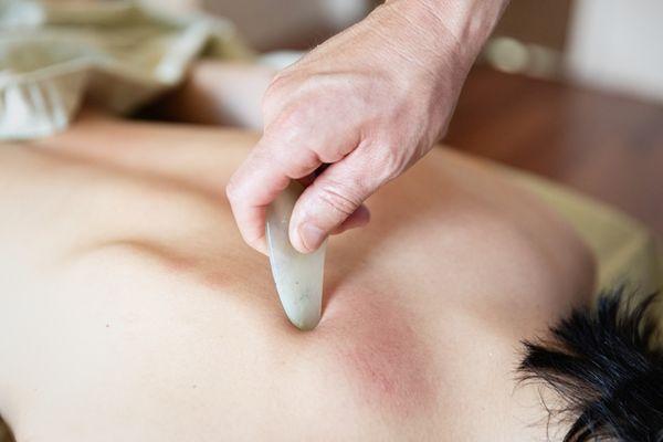 Using a Jade Gua Sha Tool to aid in the  release muscle tension and Improve circulation.