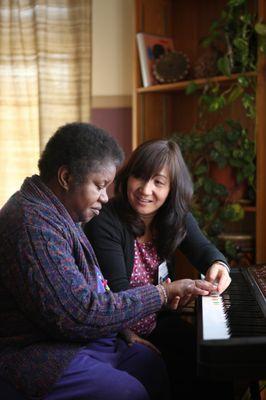 Earthtones music therapist teaching a client how to play piano.