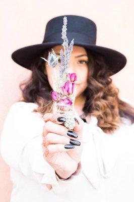 Owner, Lídia with sage smudge wand and crystal she creates with reiki intentions