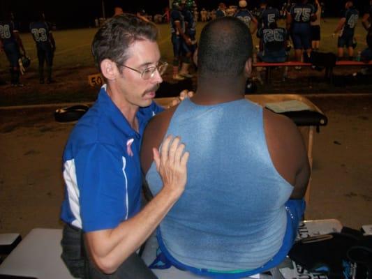 Dr. Austin adjusting a Foxes player's shoulder on the sidelines.