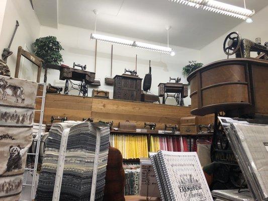 Vintage machines on display above the mostly solid color wall of fabrics.