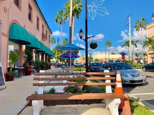 Tables with umbrellas provide seating along way east side of the coffee shop.