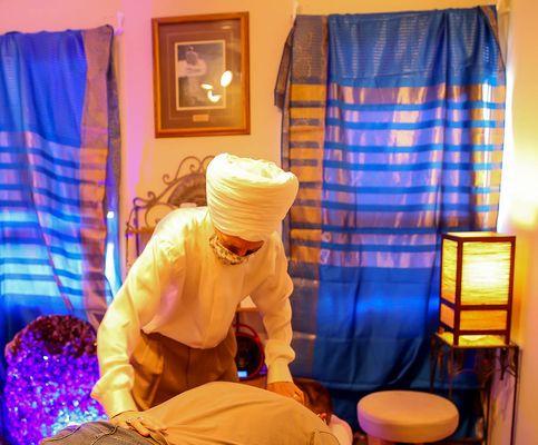 Dr Khalsa doing cranio-sacral adjustment in their amethyst crystal healing room