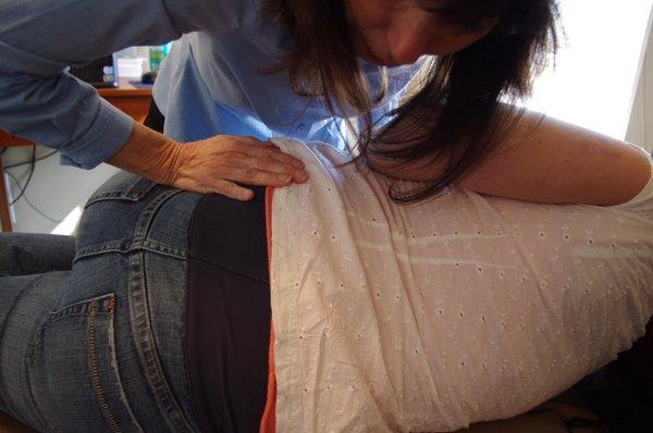 A pregnant patient relaxes for a pelvic adjustment that helps reduce/correct spinal subluxations.