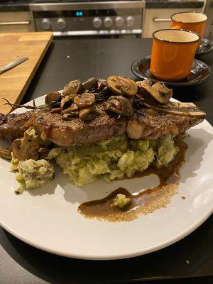 Ribeye over mashed potatoes topped sautéed mushrooms.