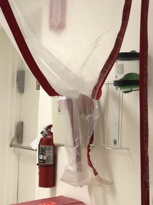 The curtain of this "clean er room" had its sheet held using the sharps container