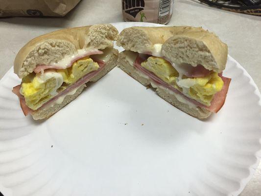 Egg and ham breakfast sandwich with cheese on plain bagel.