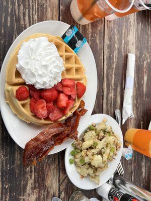 Belgium waffle with fresh strawberries and whipped cream, bacon and potatoes.