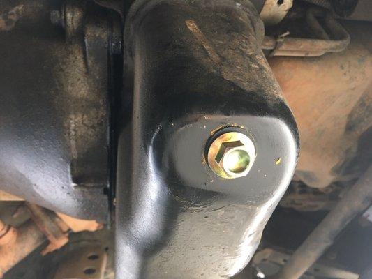 New oil drain plug that I installed. Note oil behind the pan on the transmission. They tried to claim my engine was leaking.