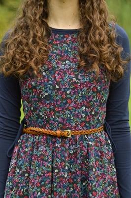 Floral sundress worn over a navy shell and belted with a tan woven belt