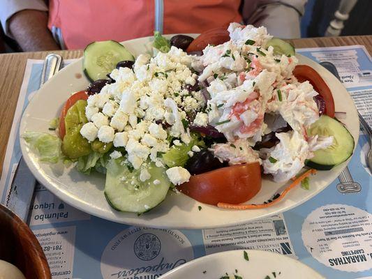 Greek salad topped with seafood salad