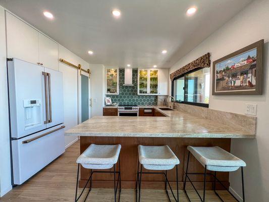 Quartzite Taj Mahal countertops, two-toned cabinets, a beautiful green hexagon backsplash, and a convenient walk-in pantry.