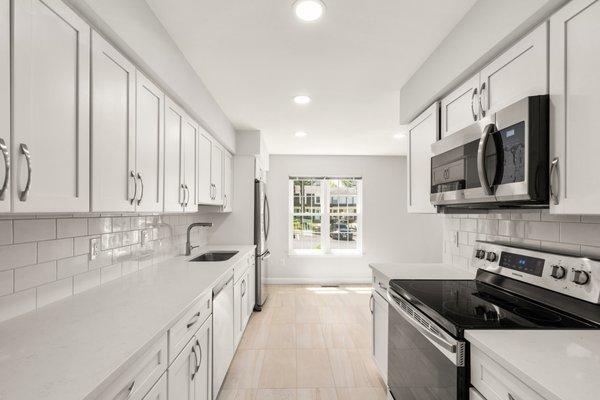 White galley kitchen with traditional white subway tile. design and installed by Tile Center