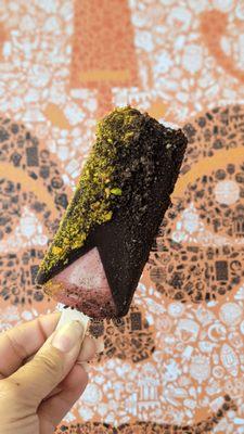 Vegan strawberry paleta dipped in dark chocolate and topped with oreo crumbles and pistachios