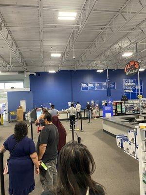 Long line and only 1 cashier working even though there are at least 20 employees in the store standing around