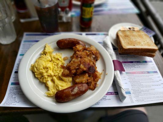 Scrambled eggs, hash browns, sausage and toast.