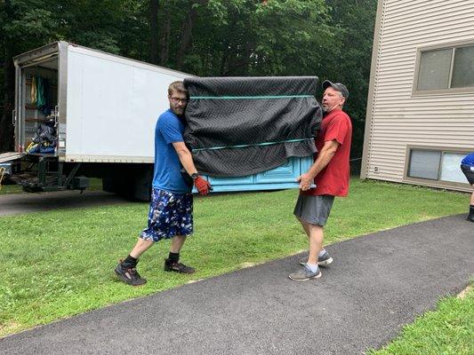 Crew members moving a loaded dresser