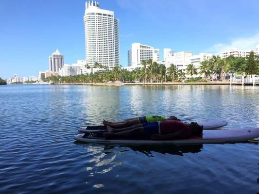 Paddleboard yoga under a bridge with a cup of wine