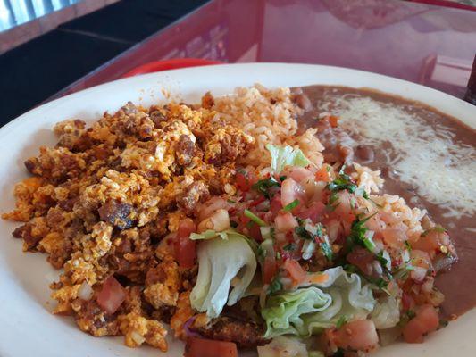 Huevos con chorizo frijoles fritos y pico de gallo con tortillas de harina