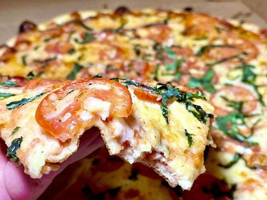 Fresh Tomato & Basil slice after a few bites showing crust thickness