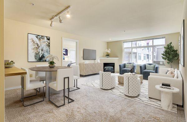 Staged living room and dining room featuring a fire place with access to a private patio/balcony.