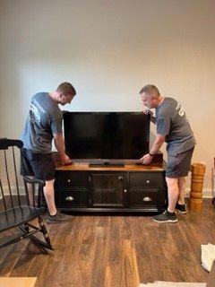 Team work moving and placing flat screen TV.