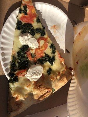 Vegetarian slice of white sauce pizza with spinach, tomato, goat cheese