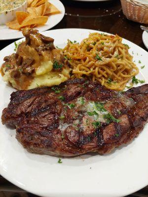 Ribeye steak with garlic noodles and mash potatoes with mushroom gravy. Cooked perfectly. So good!