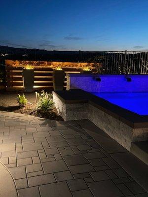 Personalize lighted pots in front of a natural wood, equipment wall, displaying spa with water feature, and colored lights!