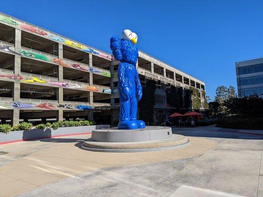 Statue, parking structure and outdoor seating with orange umbrellas