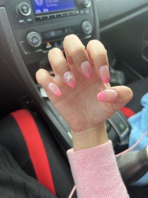 Pink french tip nails with a cute star on my ring finger