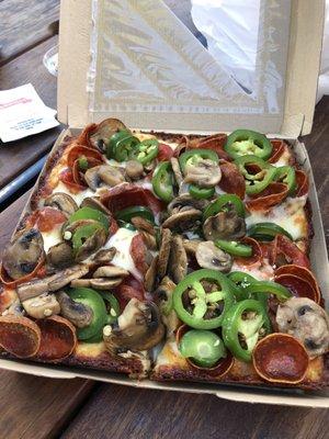 Pizza with pepperonis, jalapeños and mushrooms.