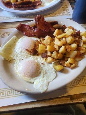 Two eggs over easy, bacon, and home fries