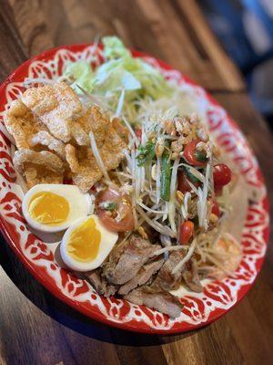 papaya salad with mu yo (pressed pork sausage), deep-fried pork rinds, pickled bamboo shoots, culantro, and boiled eggs