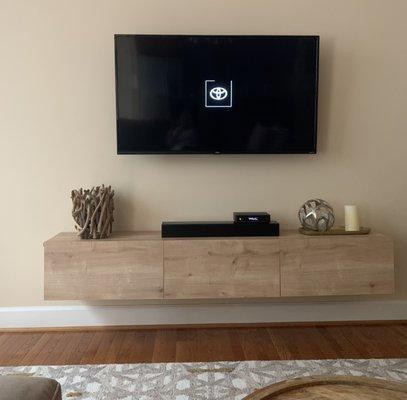 TV, sound bar, cable box and floating shelf.