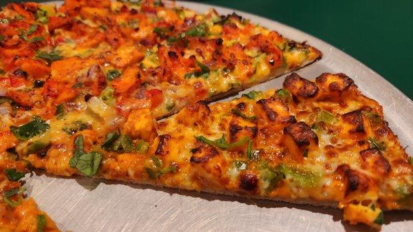 Closeup of thin crust Half and half pizza (chicken tandoori and shahi paneer)