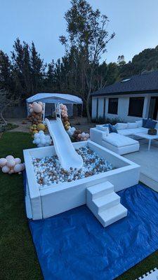 White ball pit and slide with beige/white/clear balls.