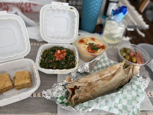 Baklava, tabbouleh,hummus, pickles and falafel sandwich.