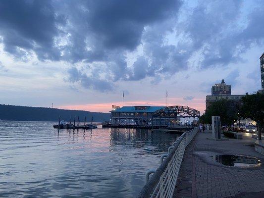 Taco restaurant to the right of the building on the water, with fantastic river sunset. Car with headlights on is at valet parking.