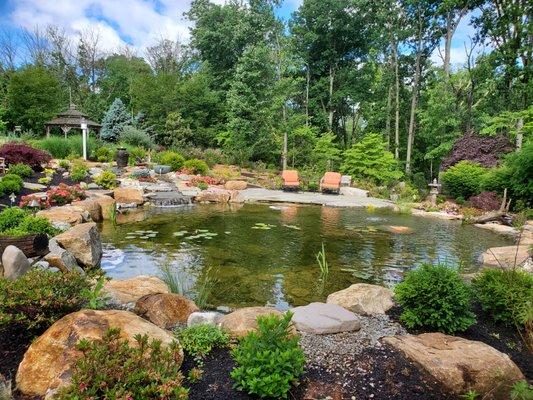 Large backyard pond with natural stones and vibrant, colorful landscaping