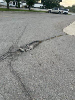 Major pothole at a business with lots of traffic.