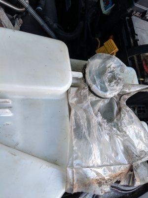 They used a plastic bag and zip tie as a cover for the windshield washer fluid.