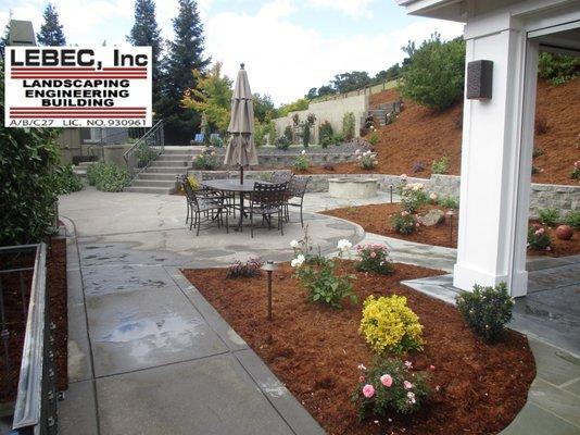 Multiple retaining walls, walkways, landscaping, bbq and outdoor kitchen, seating walls and all new landscaping.