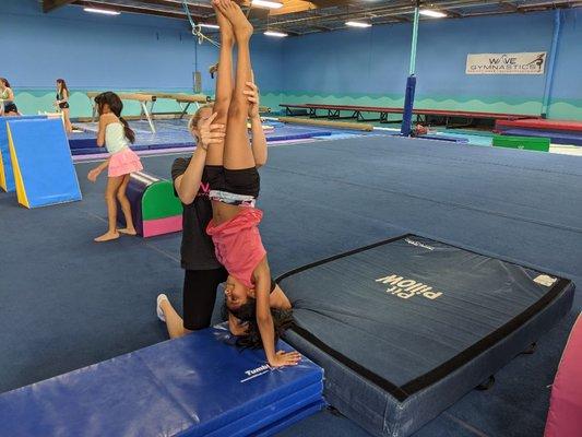 Coach helping on a handstand.