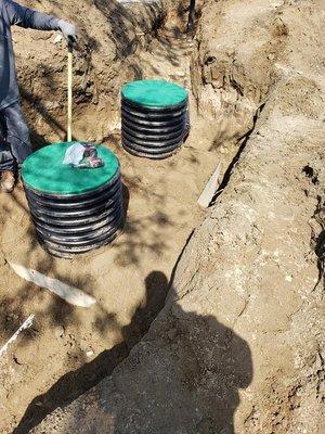 Installing risers to keep Septic tank lids on the same level as the ground. Adding dirt all around to have a flat surface.